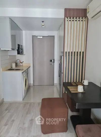 Modern compact kitchen with washing machine and dining area in stylish apartment.