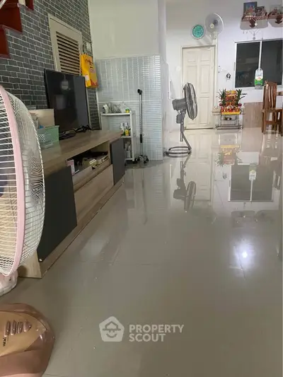 Spacious living room with modern decor and glossy tiled floors, featuring a stylish entertainment unit and dining area.