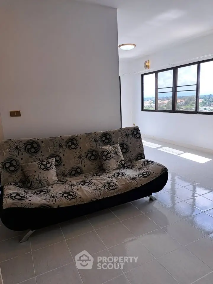 Bright living room with modern sofa and large window offering scenic view