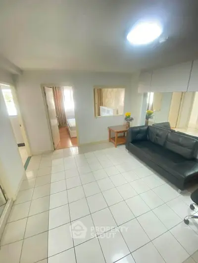 Spacious living room with modern sofa and tiled flooring, perfect for cozy gatherings.