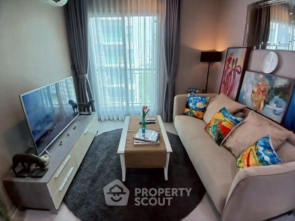 Chic living room with modern decor, vibrant cushions, and a large TV, perfect for relaxation.