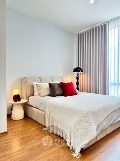 Elegant bedroom with cozy bed, stylish decor, and natural light through large window.