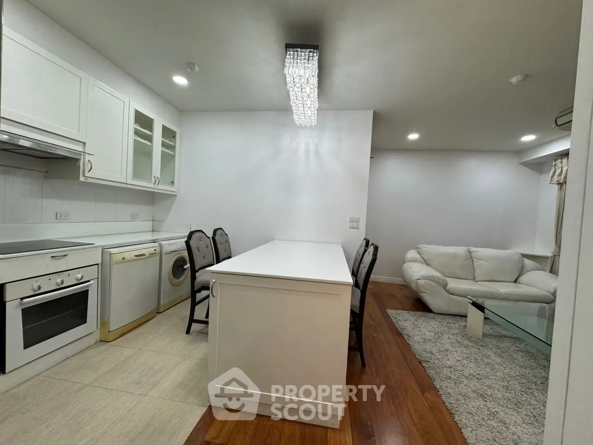 Modern open kitchen with dining area and cozy living room featuring elegant lighting.