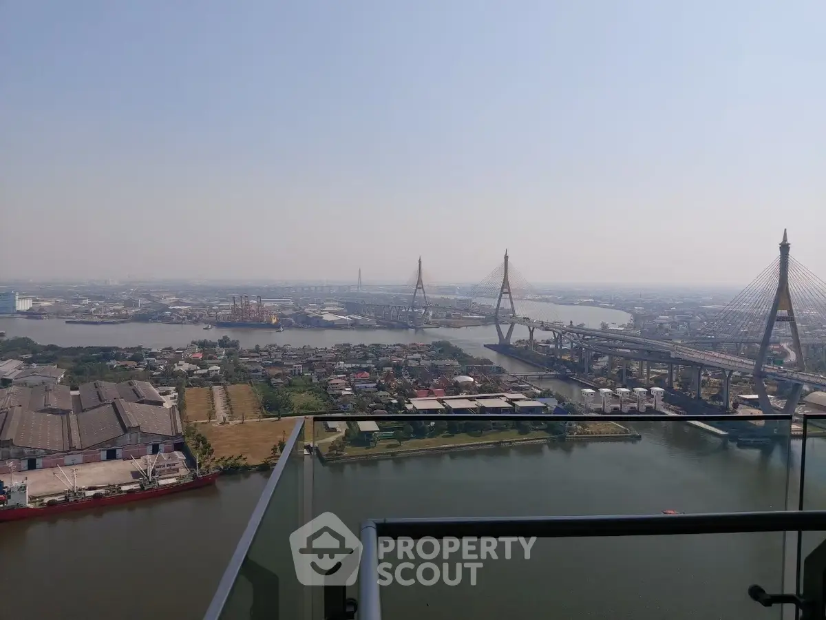 Stunning high-rise balcony view overlooking river and cityscape with iconic bridge.