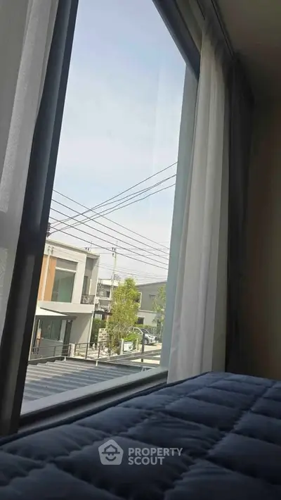 Modern residential view from bedroom window with clear sky and contemporary houses.