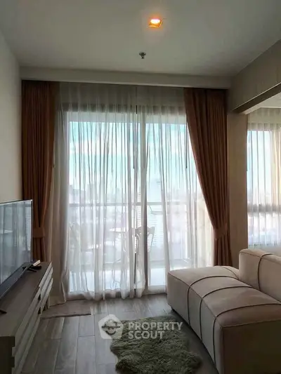 Modern living room with large windows and balcony view, featuring stylish furniture and elegant curtains.