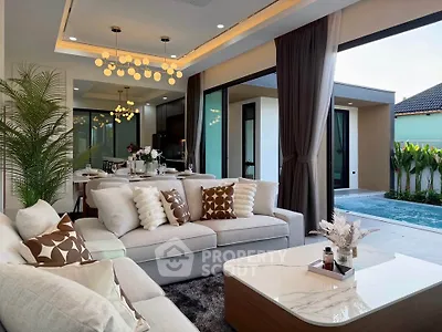 Luxurious open-plan living room with pool view, elegant decor, and modern lighting in a stylish home.