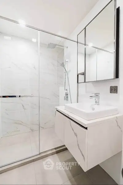 Modern bathroom with sleek design, featuring a glass shower enclosure and elegant vanity.