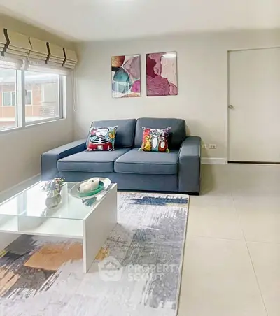 Modern living room with stylish sofa, abstract art, and large window for natural light.