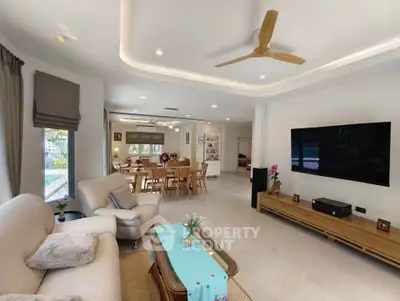 Spacious modern living room with elegant decor and large TV, perfect for family gatherings.