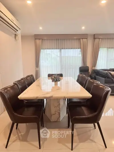 Elegant dining area with marble table and leather chairs in modern living room.