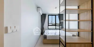 Modern bedroom with large window and built-in shelving, offering a bright and airy atmosphere.