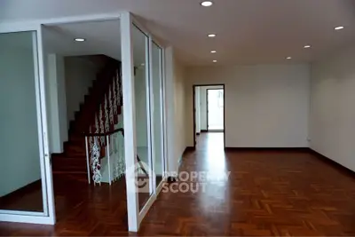 Spacious open-plan living area with elegant wooden flooring and staircase.