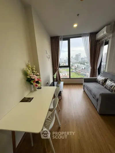 Modern living room with city view, featuring cozy sofa and dining area, perfect for urban living.