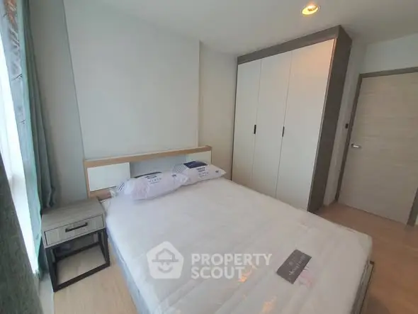 Modern bedroom with sleek design and ample natural light, featuring a spacious wardrobe and cozy bed.