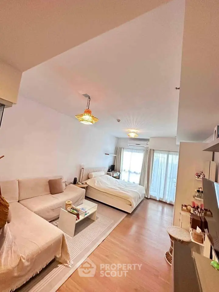 Spacious studio apartment with cozy living area and large windows.