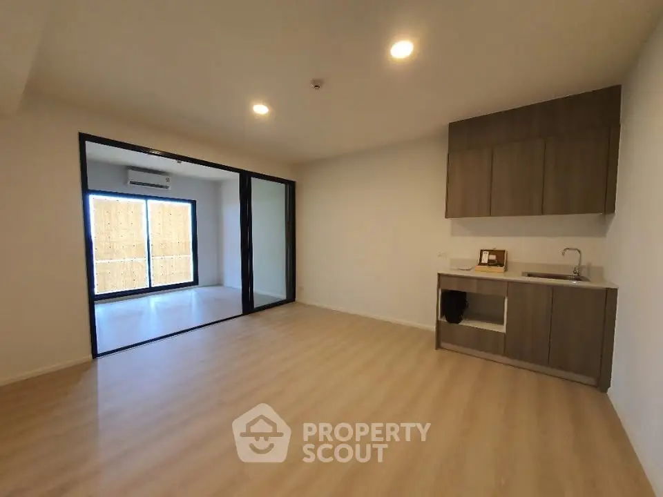 Modern open-layout living room with wooden flooring and kitchenette