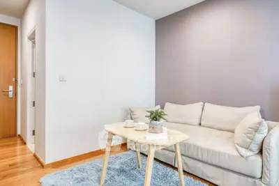 Cozy living room with modern sofa and wooden coffee table on plush rug.