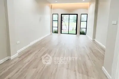 Spacious and well-lit living room with elegant hardwood flooring and modern French doors leading to a serene outdoor view, perfect for a chic and comfortable lifestyle.