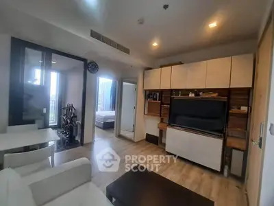 Modern living room with sleek furniture and open layout, featuring a view into the bedroom.