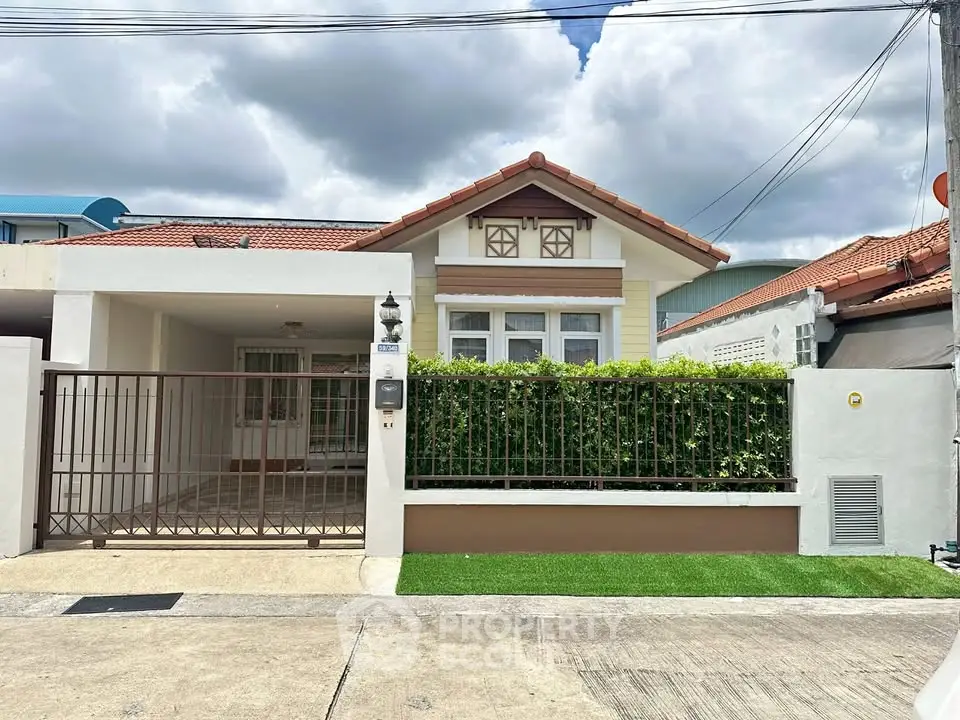 Charming single-story house with red-tiled roof and lush green hedge in a serene neighborhood.