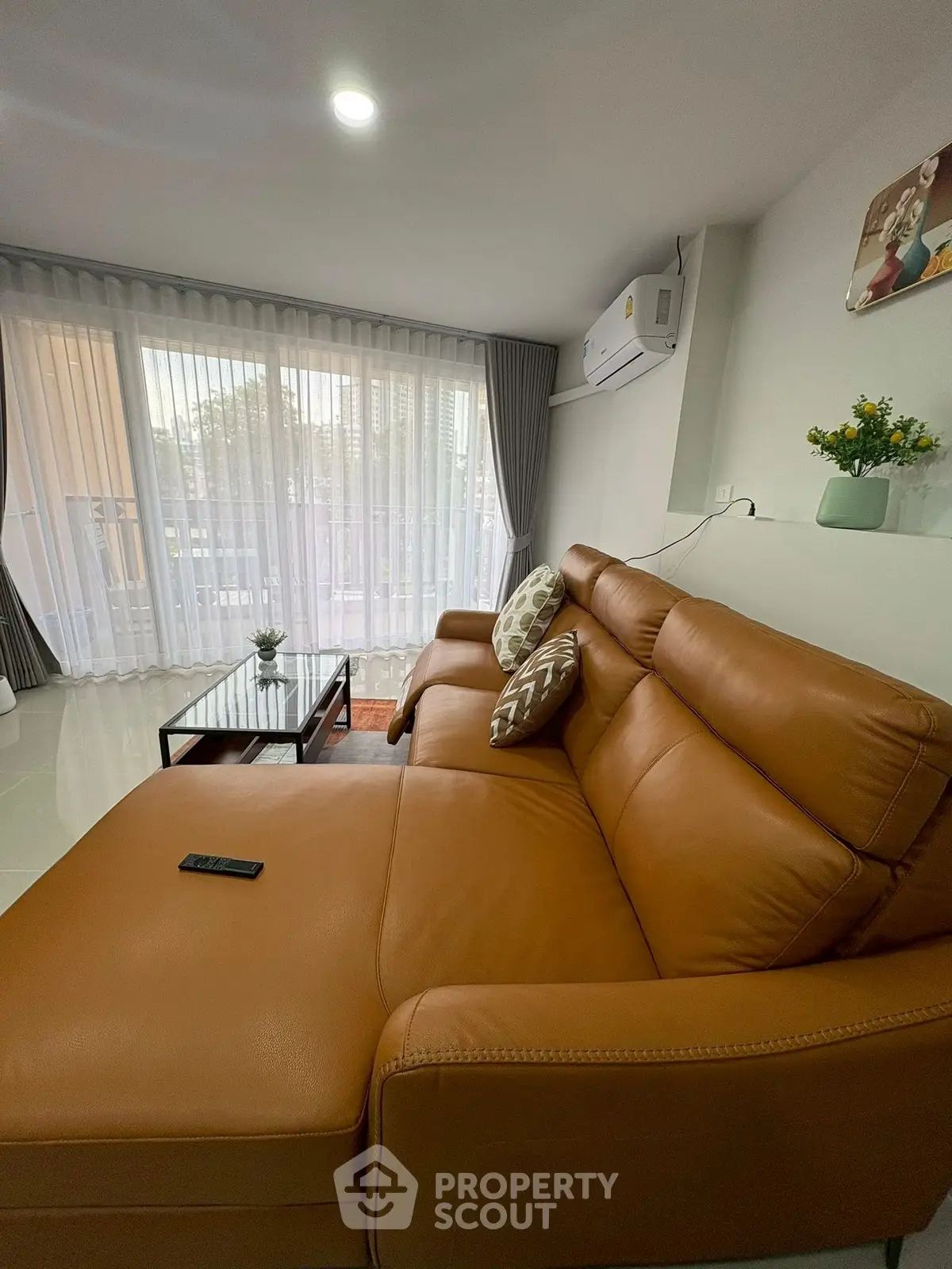 Spacious living room with leather sofa and large windows offering natural light