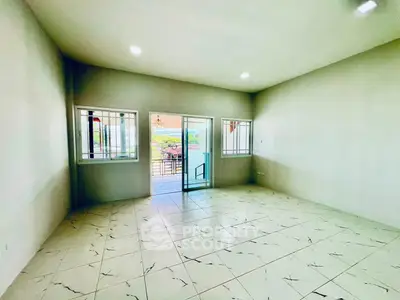 Spacious empty room with tiled floor and balcony access, ideal for customization.