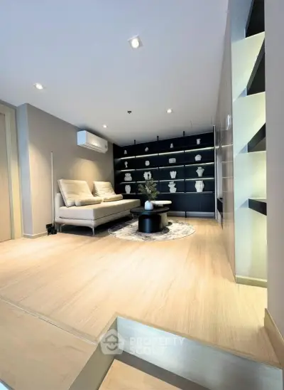 Modern living room with elegant decor and built-in shelving, featuring a cozy sofa and stylish lighting.