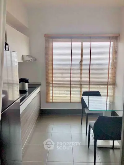 Modern kitchen with sleek cabinetry, glass dining table, and large window for natural light.