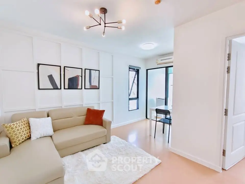 Modern living room with stylish decor and natural light, featuring a cozy beige sofa and chic wall art.