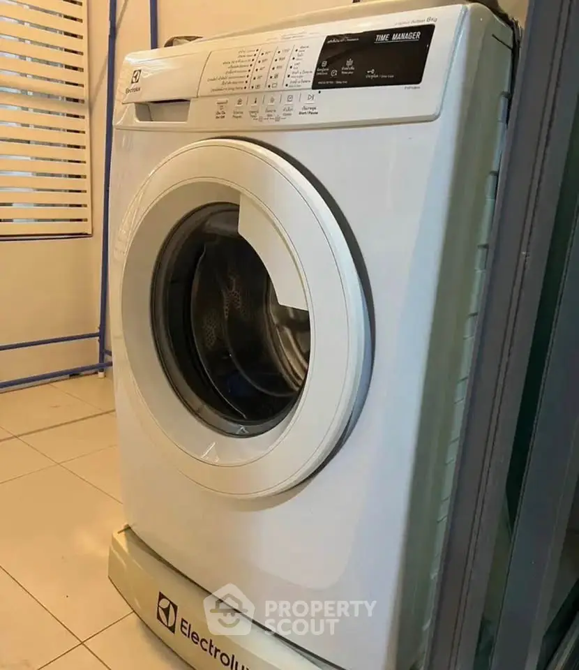 Modern Electrolux washing machine in a sleek laundry area with tiled flooring.