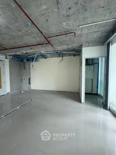 Spacious unfinished interior with modern potential, featuring large windows and open layout.