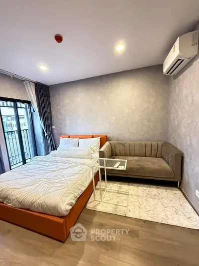 Modern bedroom with cozy sofa and balcony view in stylish apartment.