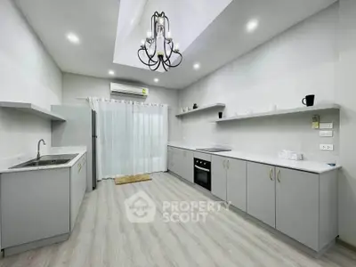 Spacious modern kitchen with sleek cabinetry and elegant chandelier lighting.