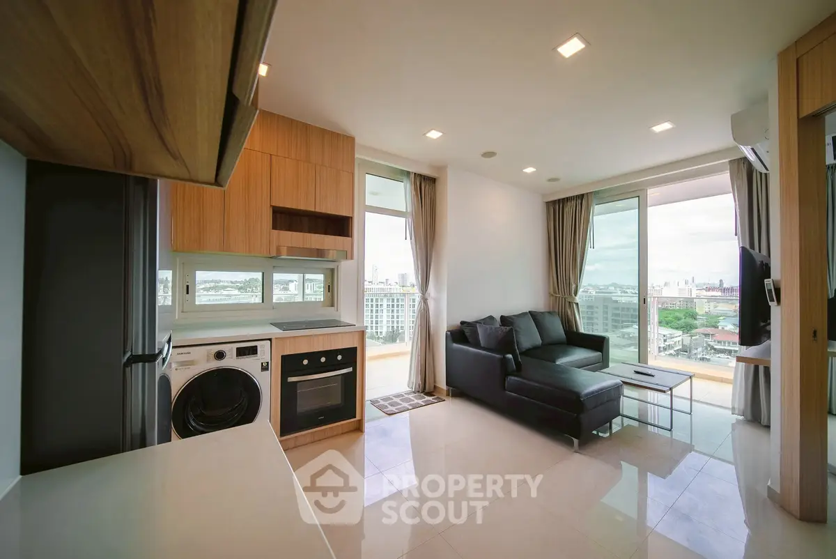 Modern open-layout living room with kitchen, featuring city view and sleek furniture.