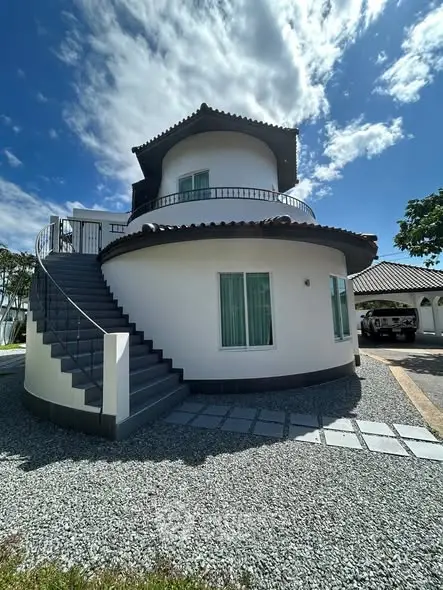 Unique round house with modern architecture and spacious balcony under a clear blue sky.