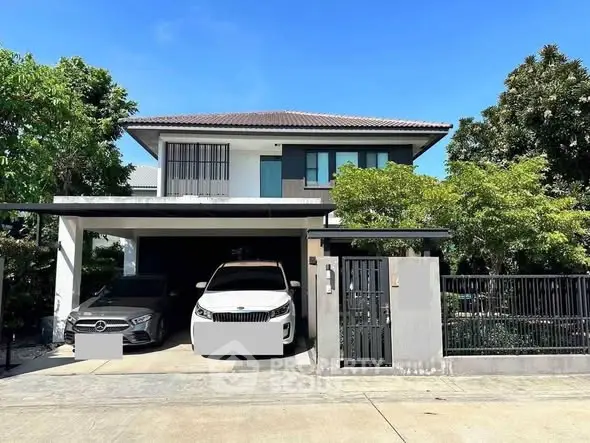 Modern two-story house with carport and lush greenery in a serene neighborhood.
