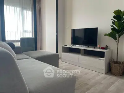 Modern living room with sleek TV stand, cozy sofa, and large window for natural light.