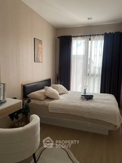 Cozy bedroom with elegant decor and natural light through large window, perfect for relaxation.