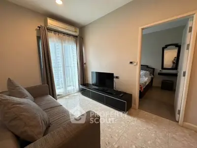 Modern living room with cozy sofa and TV, adjacent to a stylish bedroom.