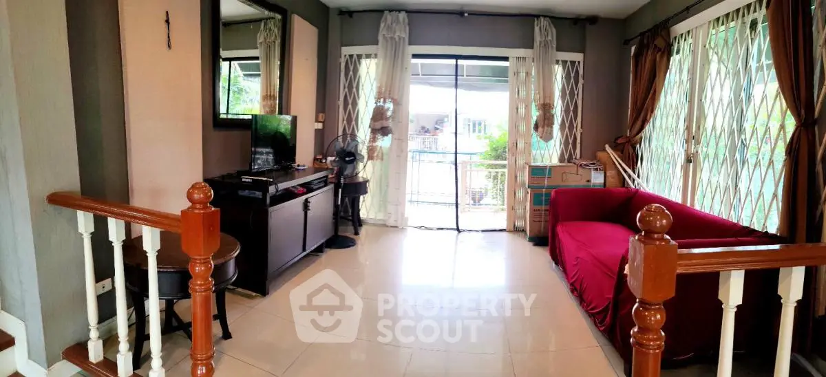 Spacious living room with large windows and balcony access, featuring elegant decor and natural light.