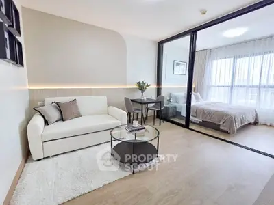 Modern studio apartment with stylish living area and cozy bedroom separated by glass partition.