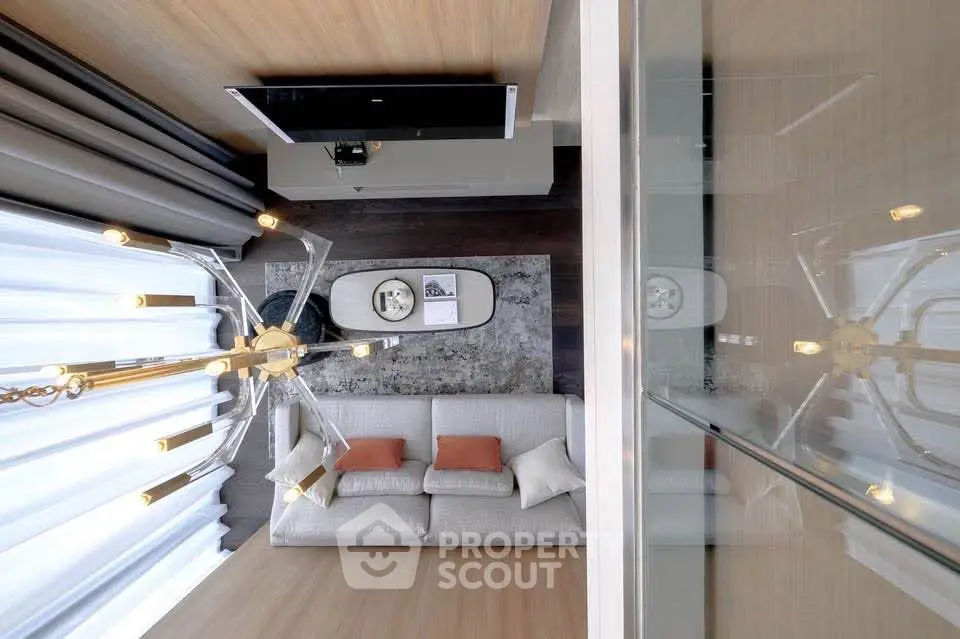 Modern living room with elegant chandelier and cozy sofa, featuring stylish decor and warm lighting.