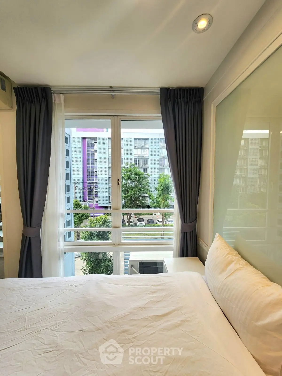 Bright bedroom with large window offering city view in modern apartment