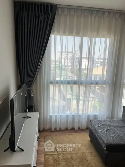 Cozy living room with large window and modern TV setup, offering a bright and inviting atmosphere.