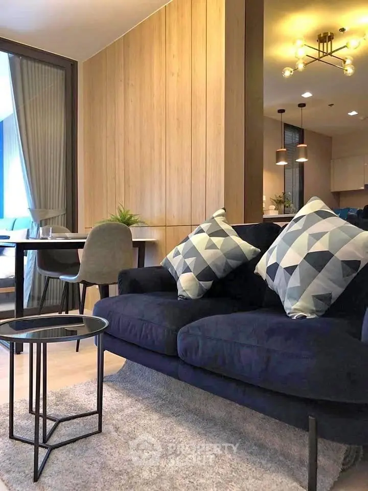Modern living room with stylish navy sofa, geometric cushions, and elegant dining area in open layout.