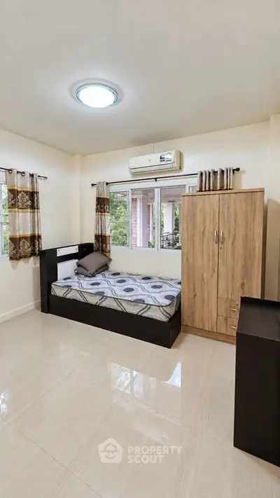 Cozy bedroom with modern furnishings and large window offering natural light.