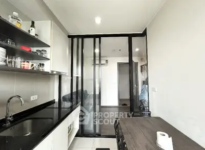 Modern kitchen with sleek black countertops and dining area in a contemporary apartment.