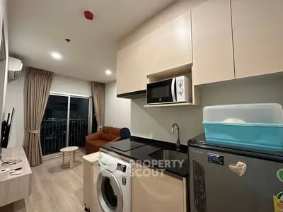 Modern apartment with open kitchen and cozy living area featuring a washing machine and microwave.