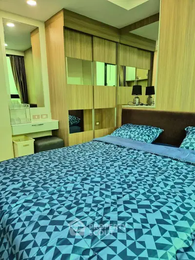 Modern bedroom with stylish blue bedding and mirrored wardrobe in a cozy apartment.